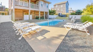 A pool area with lounge chairs, a covered deck, and a stone building in the background. - Oceanside Home w/ Private Pool, Hot Tub, Game Rm. Snag this Message in a Bottle! (Salvo)