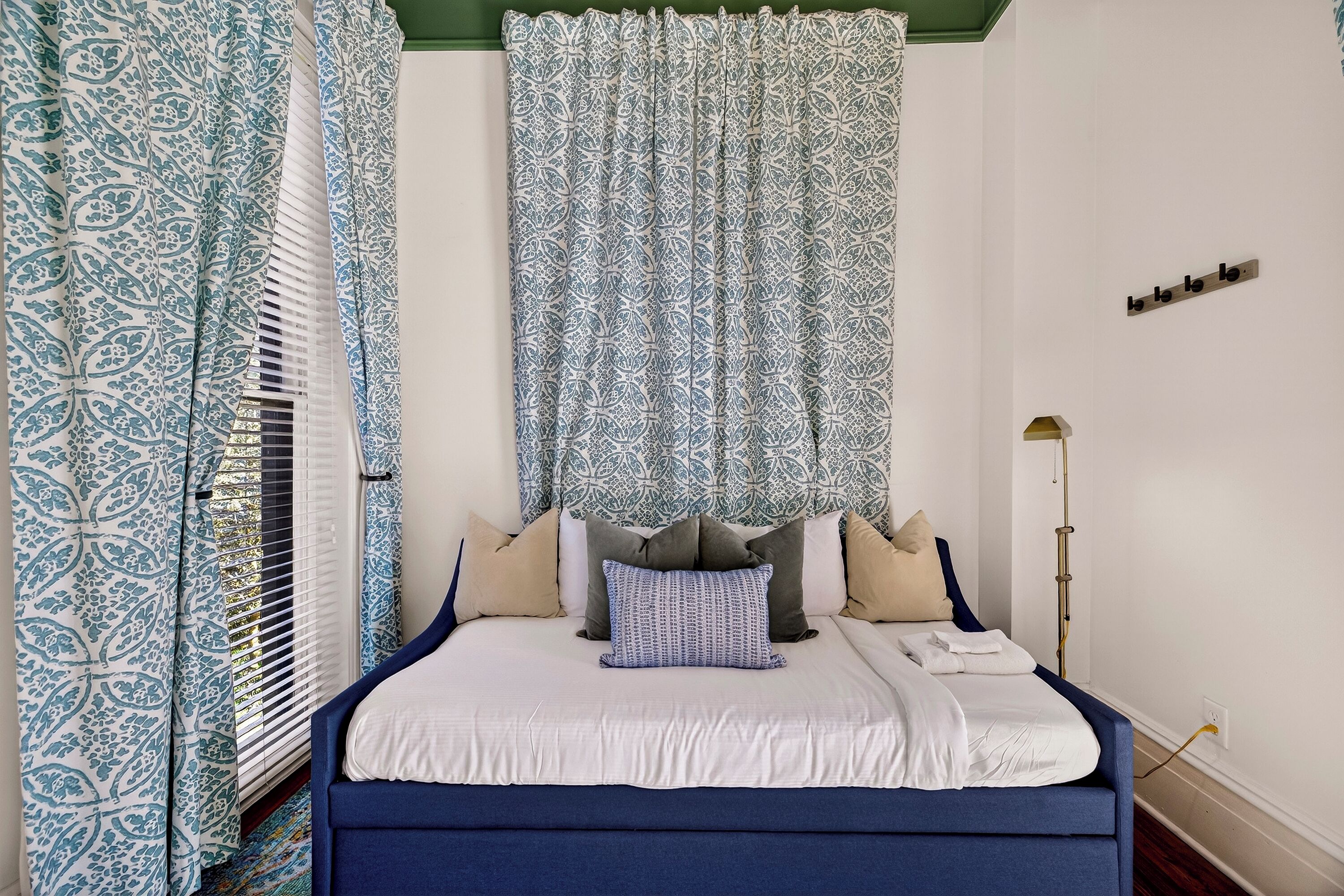 A bedroom with a bed, patterned curtains, and a bedside lamp.