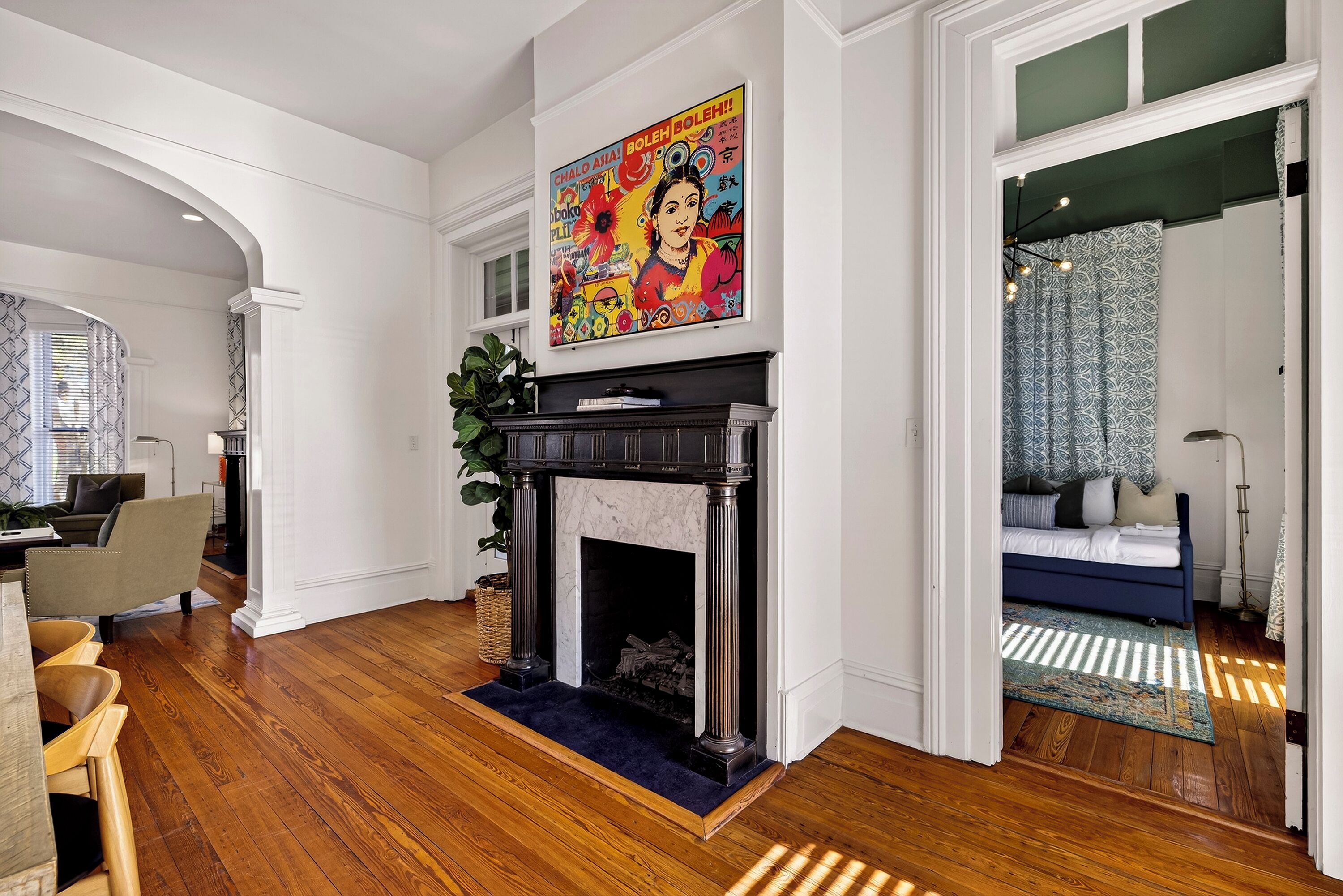 A living room with a fireplace, a painting, and a blue sofa.