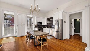 Una cocina moderna con armarios blancos, una mesa de comedor de madera y electrodomésticos de acero inoxidable.