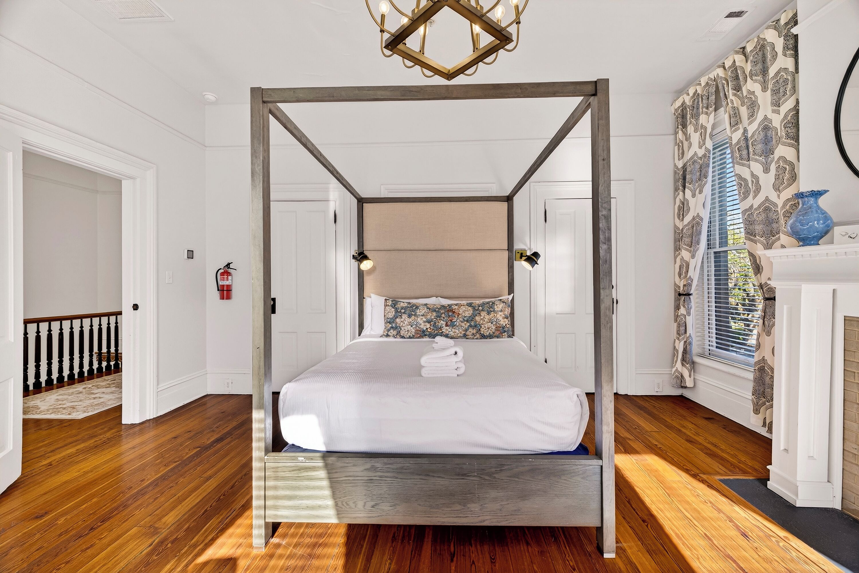 A four-poster bed with a wooden frame, white bedding, and a floral pillow.