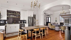Una cocina moderna con armarios blancos, un refrigerador de acero inoxidable y una mesa de comedor de madera con sillas.