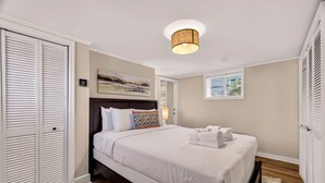 A bedroom with a bed, a headboard, a ceiling light, a window, and a closet.