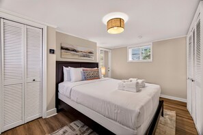 Une chambre à coucher comprenant un lit, une tête de lit, un luminaire au plafond, une fenêtre et un placard.