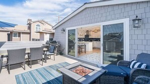 A patio area with a grill, outdoor seating, and a sliding glass door leading to a kitchen. - 304 Ruby B | Balboa Island Charmer (Newport Beach)