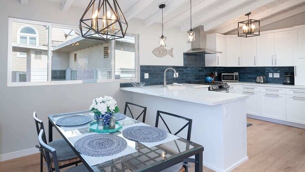 A modern kitchen with white cabinets, a central island, and pendant lighting. - 304 Ruby B | Balboa Island Charmer (Newport Beach)