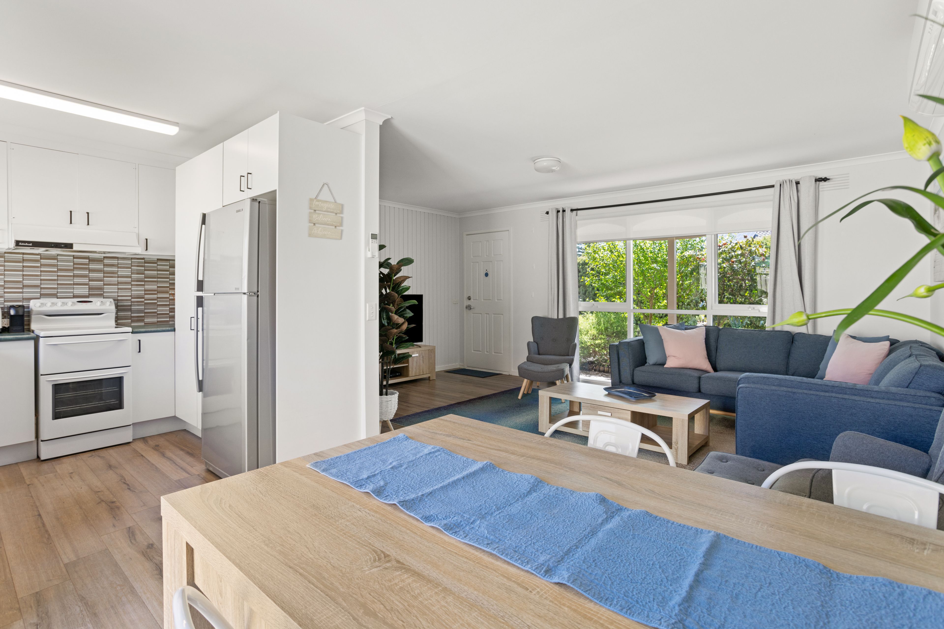 A modern kitchen with white cabinets, a built-in oven, and a stainless steel refrigerator.