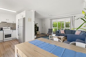 A modern kitchen with white cabinets, a built-in oven, and a stainless steel refrigerator. - Rose by the Bay  Coastal Getaway in Tootgarook (Tootgarook)