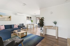 Un salon moderne comprenant un canapé, un fauteuil, une table basse et un coin repas avec des chaises et une table.
