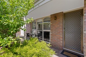 A covered outdoor seating area with brick walls and glass doors. - Rose by the Bay  Coastal Getaway in Tootgarook (Tootgarook)