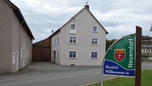 Un cartello di benvenuto ai visitatori a Neuendorf, con lo stemma araldico e un messaggio in tedesco.