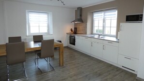 Una cucina moderna con mobili bianchi, un tavolo da pranzo in legno e due sedie.