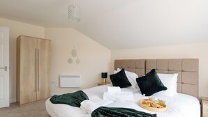 Een net opgemaakt bed met kussens, een nachtkastje met een lamp en een ontbijttray.
