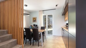 A modern kitchen with a built-in oven and a dining area with a wooden table and chairs. - [NEW] Wellness Villas with shared pool - Penelope (8C6W+HGF Rethymno, Greece)