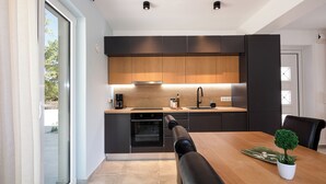 A modern kitchen with dark cabinetry, a wooden countertop, and a built-in oven. - [NEW] Wellness Villas with shared pool - Penelope (8C6W+HGF Rethymno, Greece)
