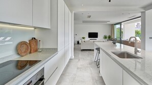 A modern kitchen with a central island, a built-in oven, and a large window providing a view of the outdoors. - 5-bedroom Villa Near Split With Pool (Kastela)