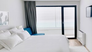 A modern bedroom with a large bed, a blue chair, and a view through a sliding glass door. - 5-bedroom Villa Near Split With Pool (Kastela)