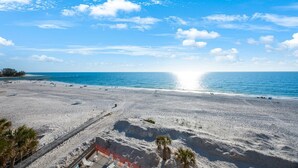 Een strand met een heldere lucht, een kalme zee en enkele mensen.