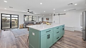 Una cocina moderna con una isla color turquesa, suelo de madera y un ventanal corredero que da a un balcón.