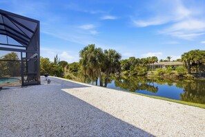 A modern outdoor area with a pool, a grill, and a view of a house and trees.