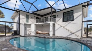 Una casa moderna con piscina, balcón y una escalera que lleva a un segundo piso.