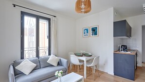 A compact living space with a sofa, dining table, and kitchenette.