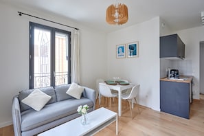 A compact living space with a sofa, dining table, and kitchenette. - New Apartment Boulogne Facing "les Passages" (Boulogne-Billancourt)