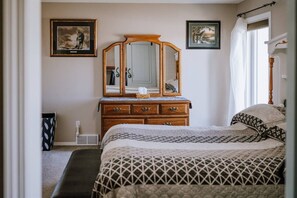A bedroom with a bed, dresser, and two framed pictures on the wall. - Cypress-3BR|Hottub|PetFriendly (Olds)