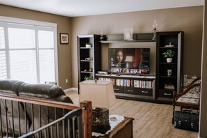 Un salon avec une télévision, des étagères à livres, un canapé et un escalier.