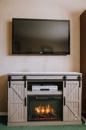 Une cheminée surmontée d’un téléviseur, un téléviseur à écran plat et une cheminée avec un feu allumé.
