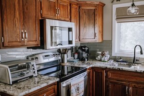 Une cuisine avec des meubles de rangement en bois, un four à micro-ondes, une cuisinière, un grille-pain et une machine à café.