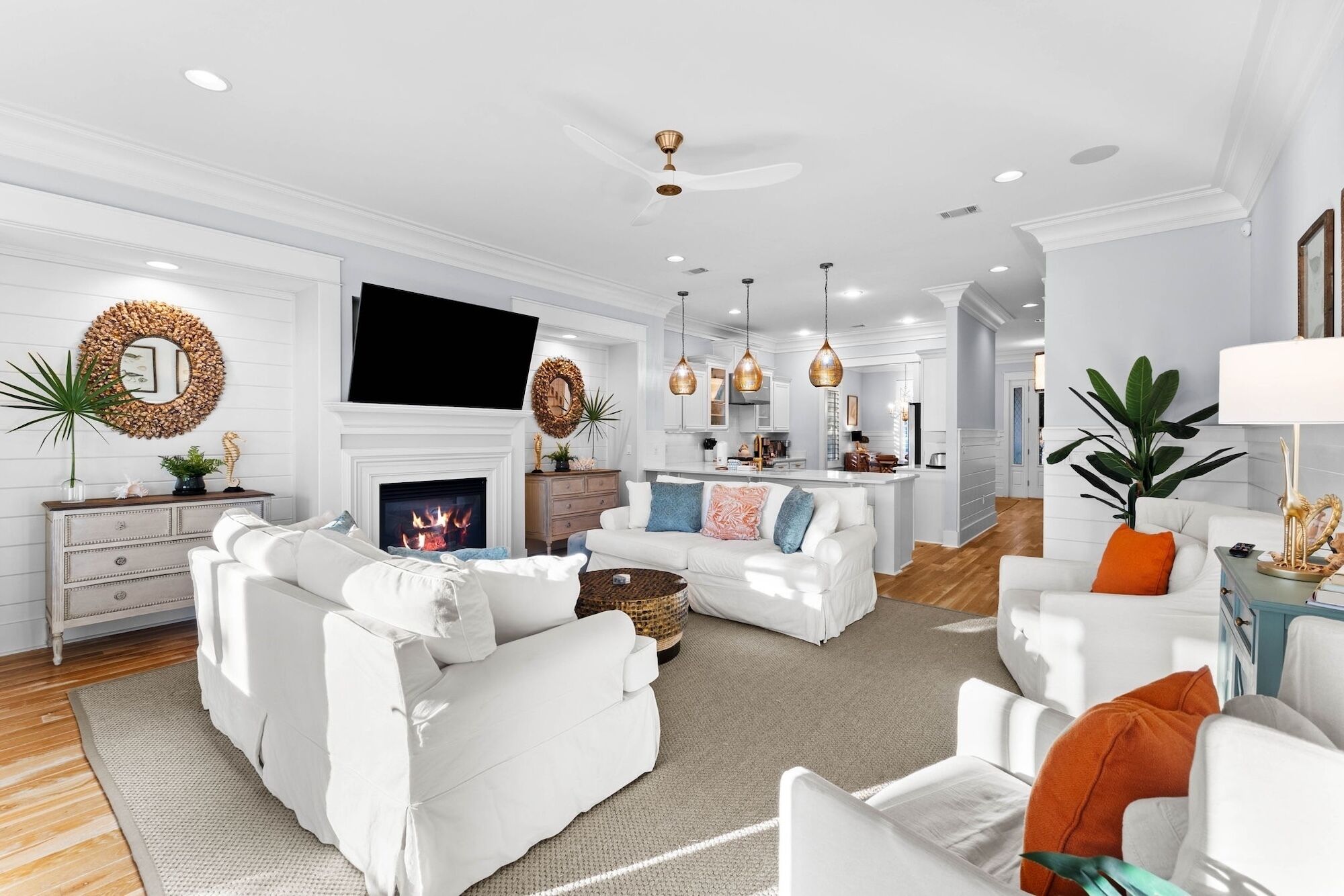 A modern living room with a fireplace, white sofas, and a television mounted above it.