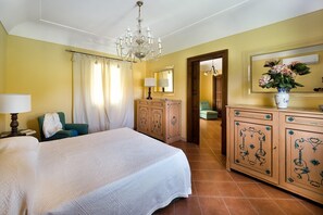 A hotel room with a large bed, a dresser, a mirror, and a chandelier.