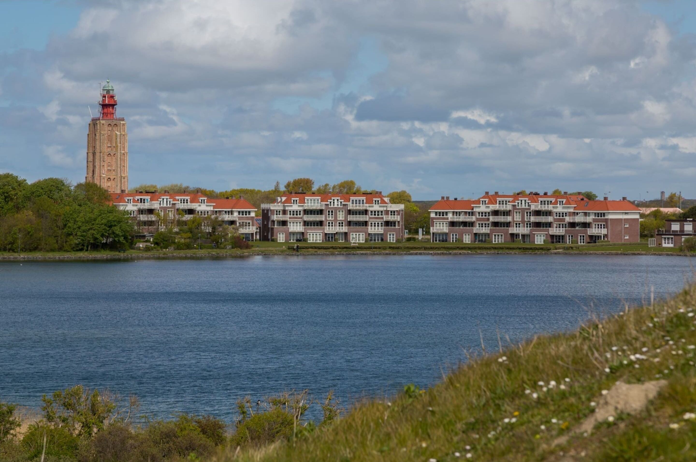 Ein Hotel am Wasser mit einem markanten Turm und mehreren Gebäuden mit roten Dächern.