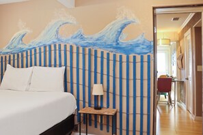 Relax in a stylish room with a large bed, unique wall design, and a cozy reading nook.