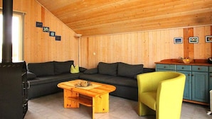 Un interior de madera con un sofá, una mesa, una silla y un armario.