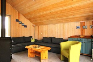 Ein Holzinterieur mit einer Couch, einem Tisch, einem Stuhl und einem Schrank.