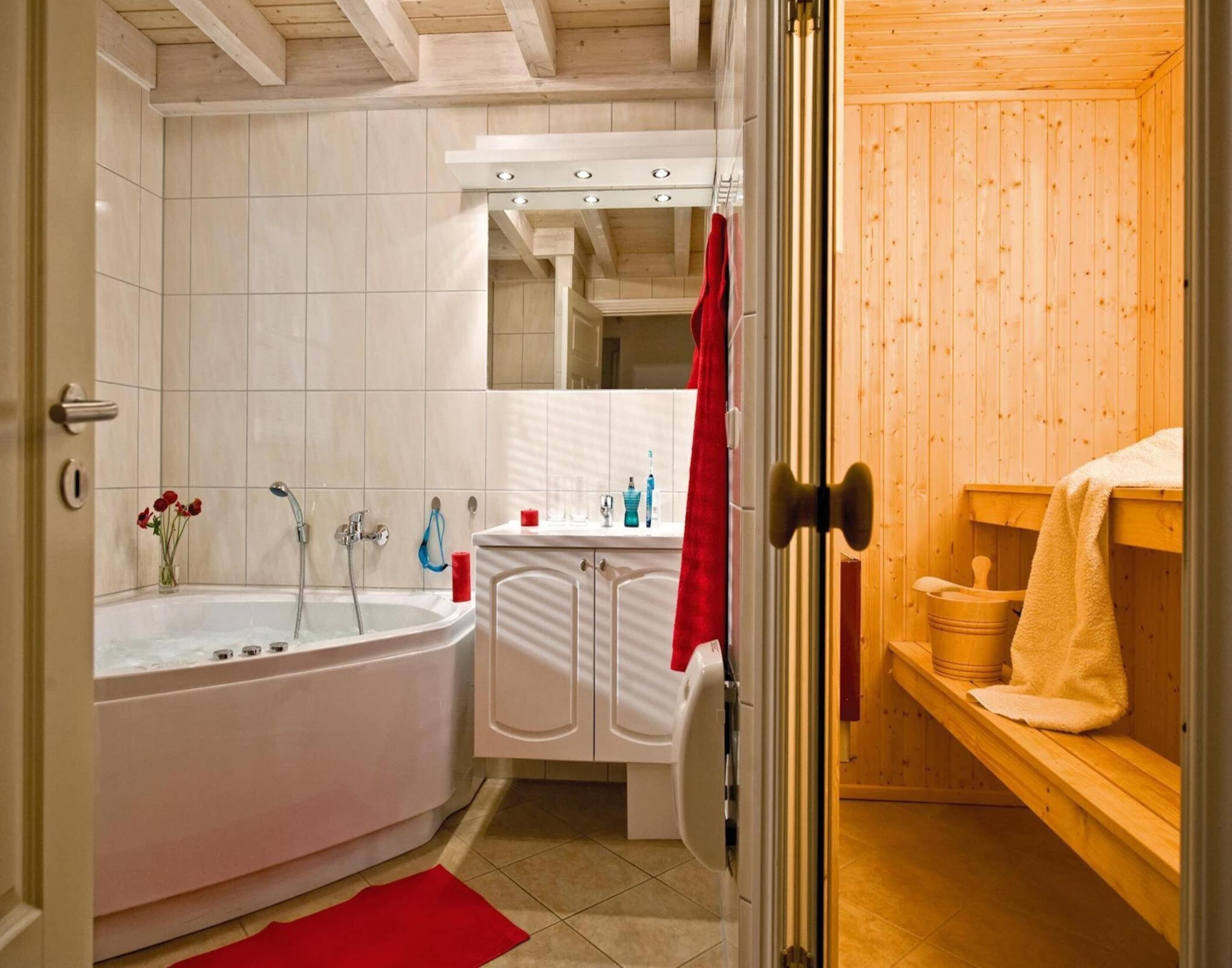 A bathroom with a bathtub, a sink, and a wooden sauna area.