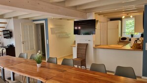 A modern kitchen with a flat-screen TV, wooden countertop, and a dining area with a large table and chairs. - XXL Ferienhaus in Bad Saarow (Bad Saarow)