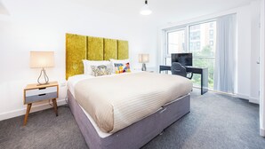 Une chambre d’hôtel avec un lit, un bureau, une télévision et une fenêtre donnant sur des immeubles.