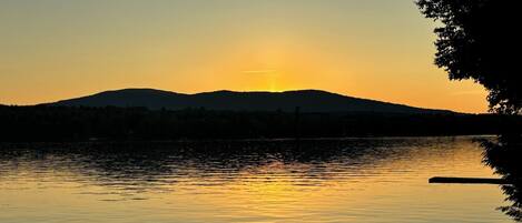 Een rustig meer bij zonsondergang, met een berg in de achtergrond.