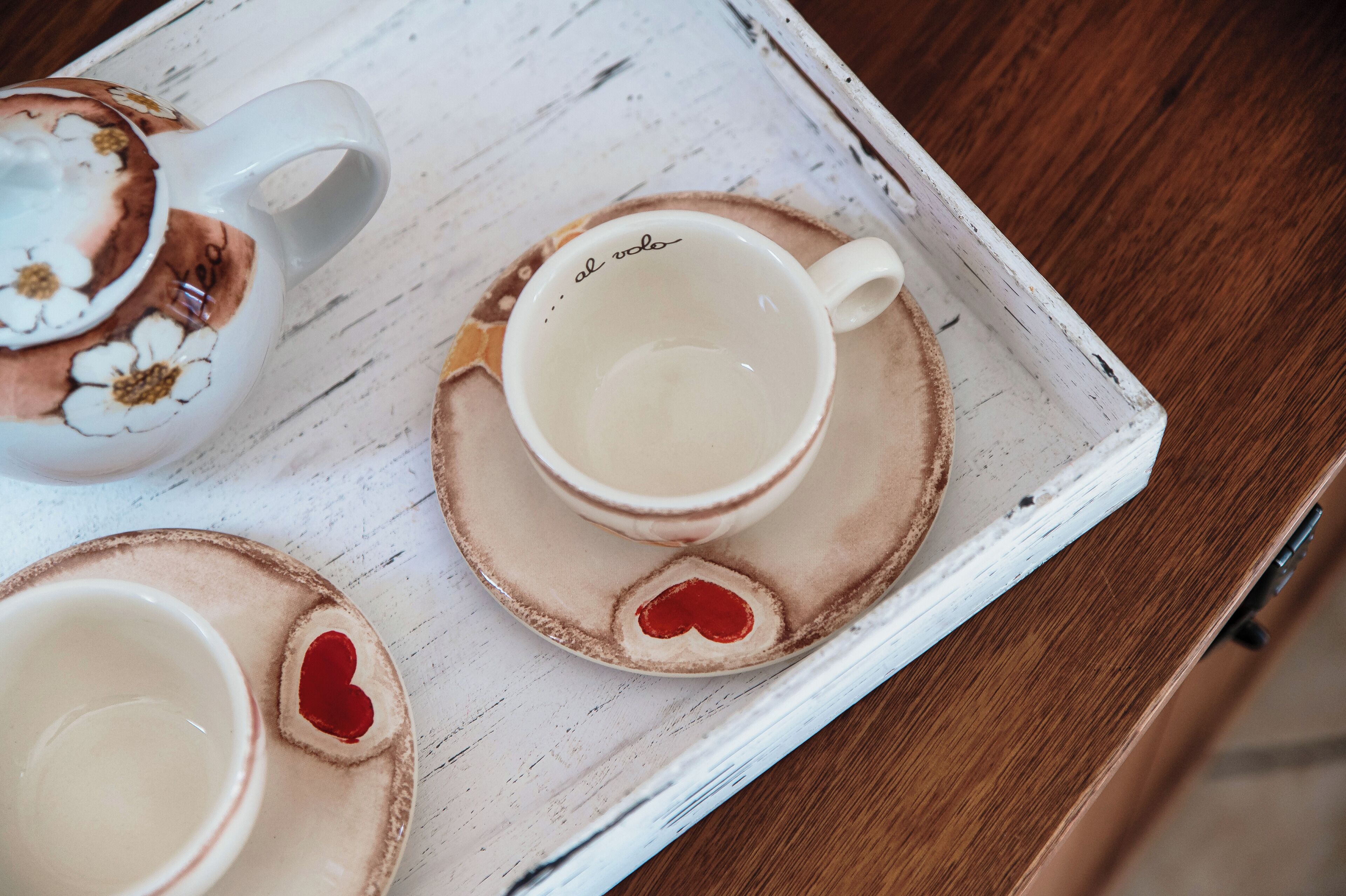 A tray with two cups and a teapot, each with a heart-shaped design on the saucer.