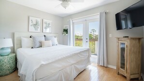 Une chambre dotée d’un grand lit, d’un ventilateur de plafond, d’une télévision et d’une porte-fenêtre coulissante donnant sur l’extérieur.