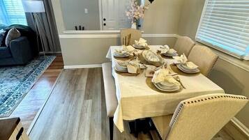 A dining area with a table set for four, a bench, and a hanging light fixture.