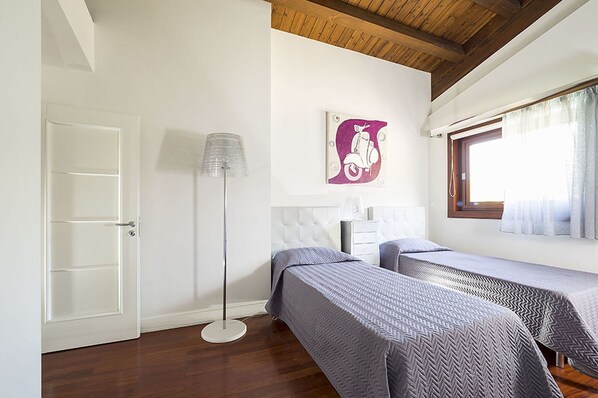 A room with two beds, a floor lamp, a door, and a window with curtains. - Villa in Agrigento Near Valley of the Temples (Agrigento)