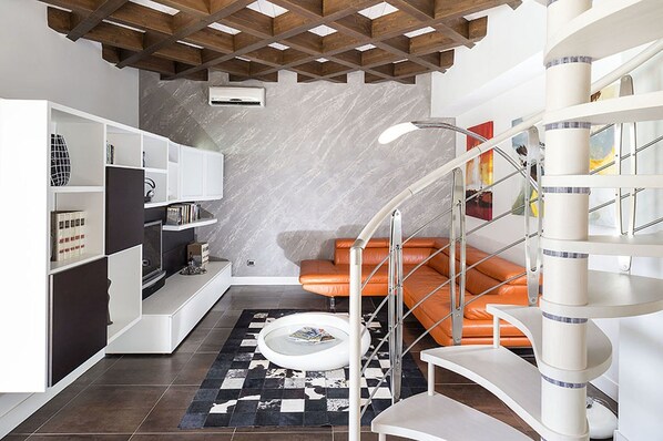 Ein modernes Interieur mit einer Wendeltreppe, einer Couch und einem Bücherregal.