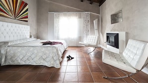 A bedroom with a bed, a white chair, a TV, and a fireplace. - Villa in Agrigento Near Valley of the Temples (Agrigento)