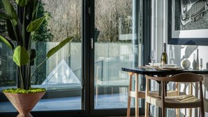 Ein stilvoller Essbereich mit Glastür zum Balkon, einem Topf mit Pflanze und einem Tisch für zwei Personen, gedeckt mit Weingläsern und einer Weinflasche.