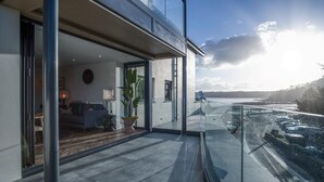 Ein modernes Interieur mit einem Glasbalkon mit Blick auf einen Parkplatz und ein Gewässer.