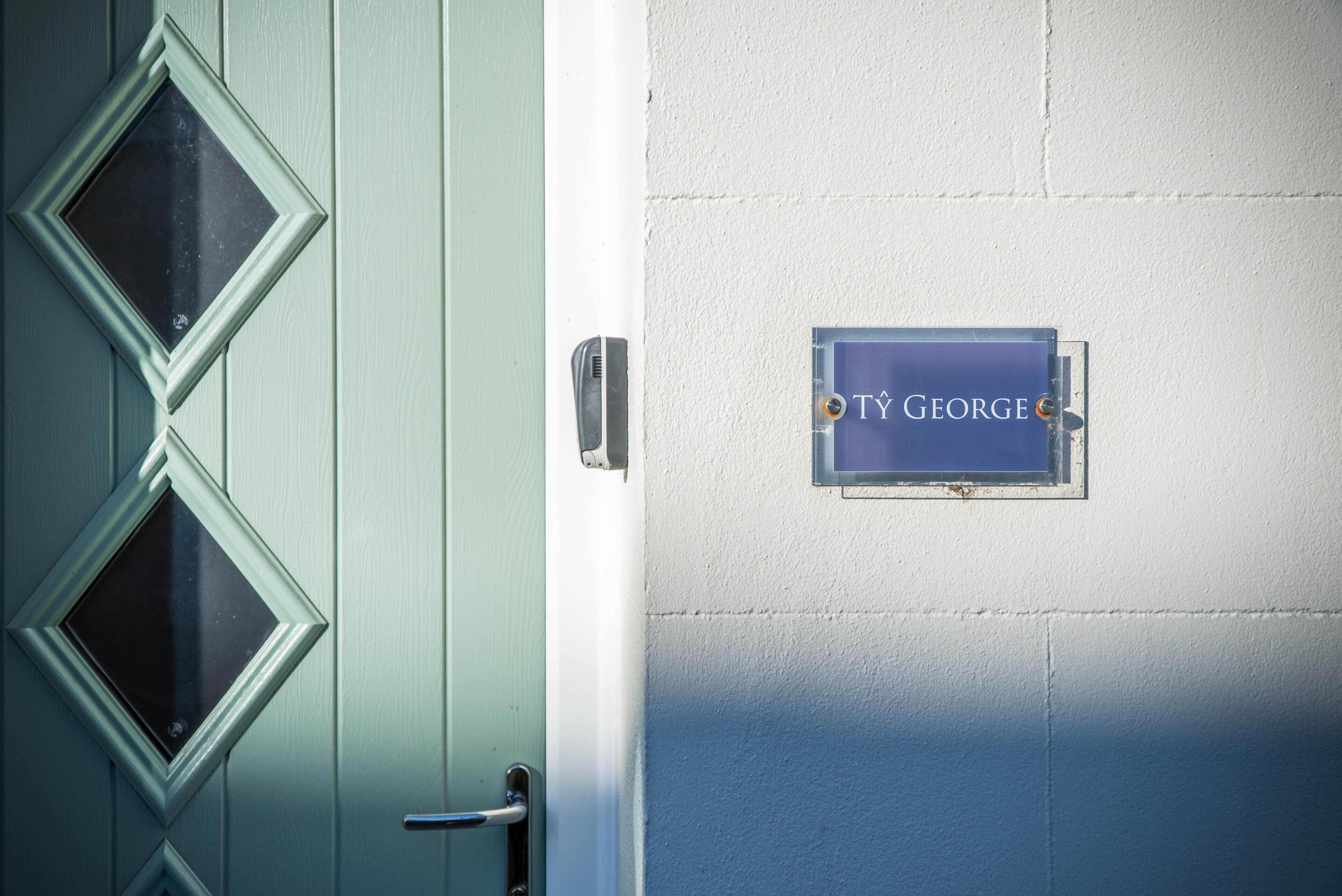 A door with a nameplate reading "TY GEORGE" and a metal handle.